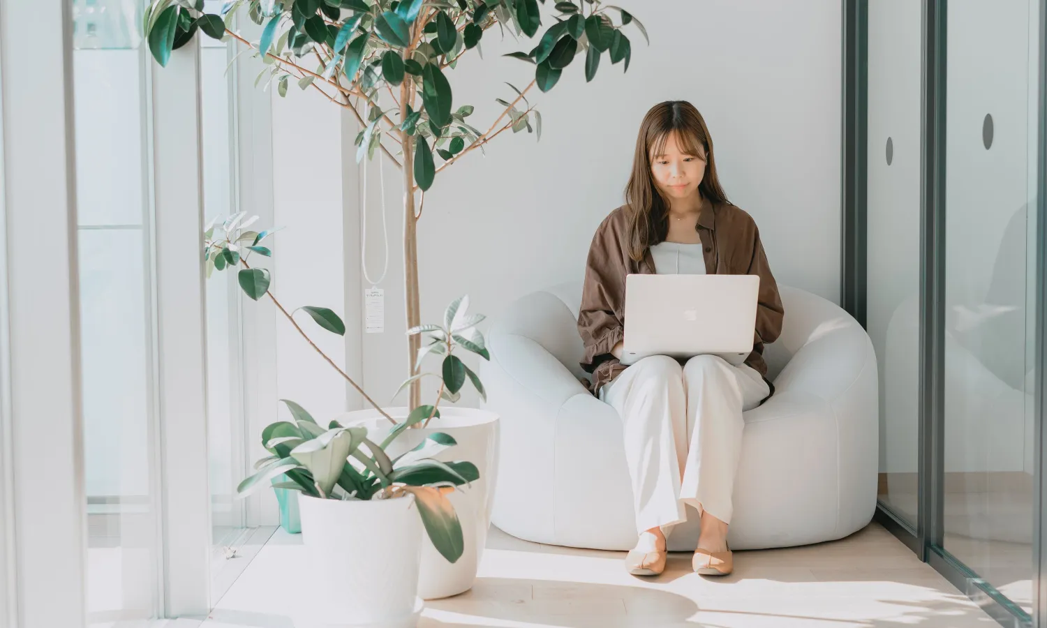 女性が1人用ソファに座ってパソコンで作業している写真