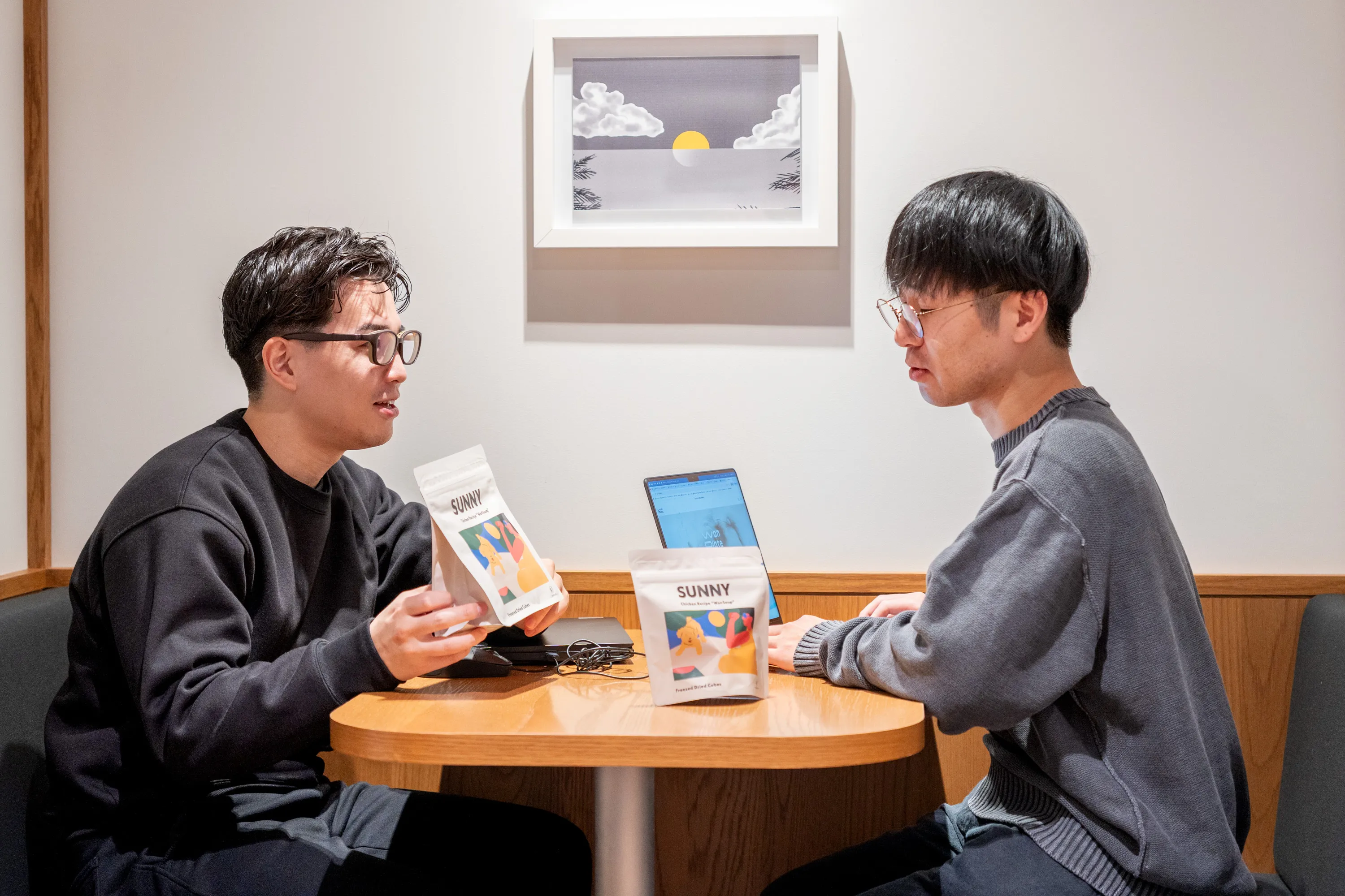 写真。男性2人が向き合って手にワンスープを持って話している写真